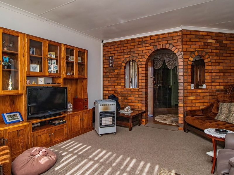 A living room featuring an exposed brick wall with arched openings and built-in wooden cabinetry, providing a traditional aesthetic.