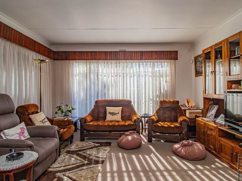 A traditional living room featuring built-in wooden cabinetry and timber pelmets, offering a classic layout with ample natural light from the large window.