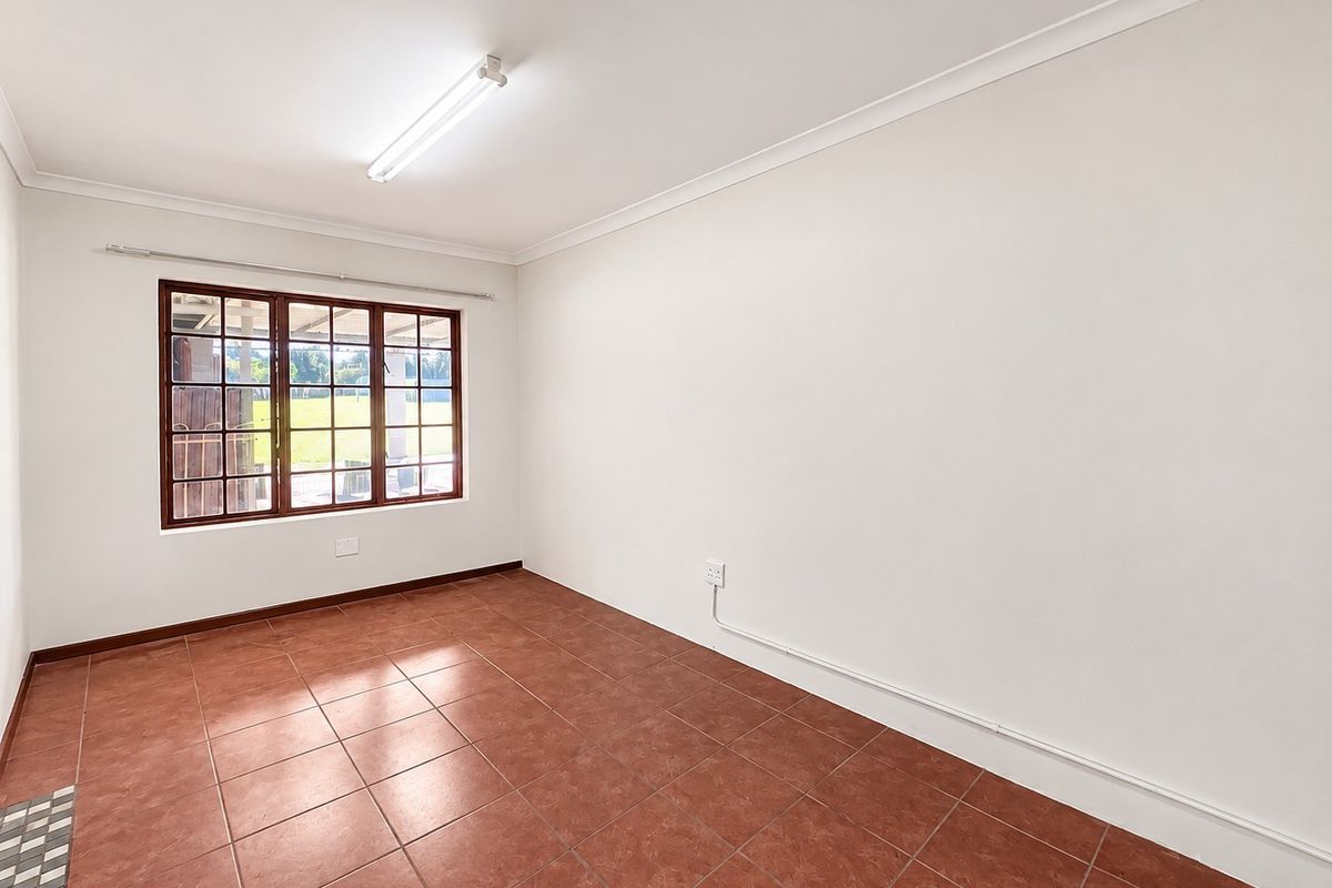 A clean, empty bedroom featuring terracotta floor tiles, a timber-framed window, and neutral walls, ready for personalization.