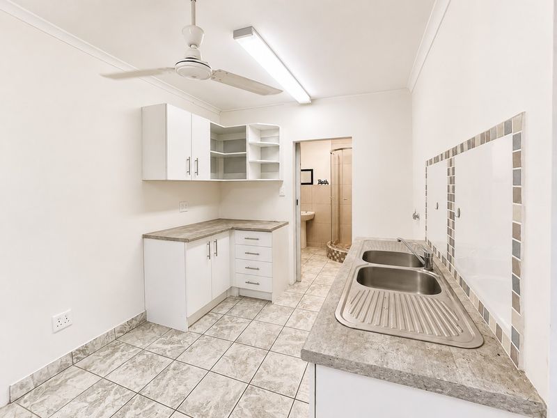Functional laundry room featuring built-in white cabinetry, laminate countertops, double stainless steel sink, and tiled flooring with direct access to an adjacent bathroom.