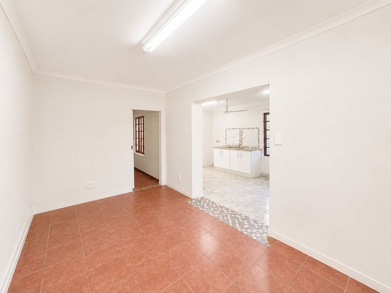 An open-plan living area featuring tiled floors and a connected kitchen space with built-in cabinetry and sink.