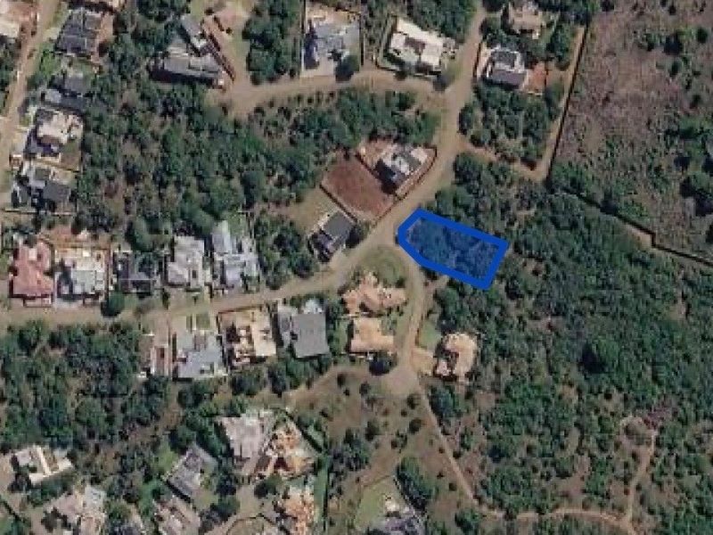 Aerial view of a vacant residential plot highlighted in blue, situated within a developed suburban estate with established vegetation.