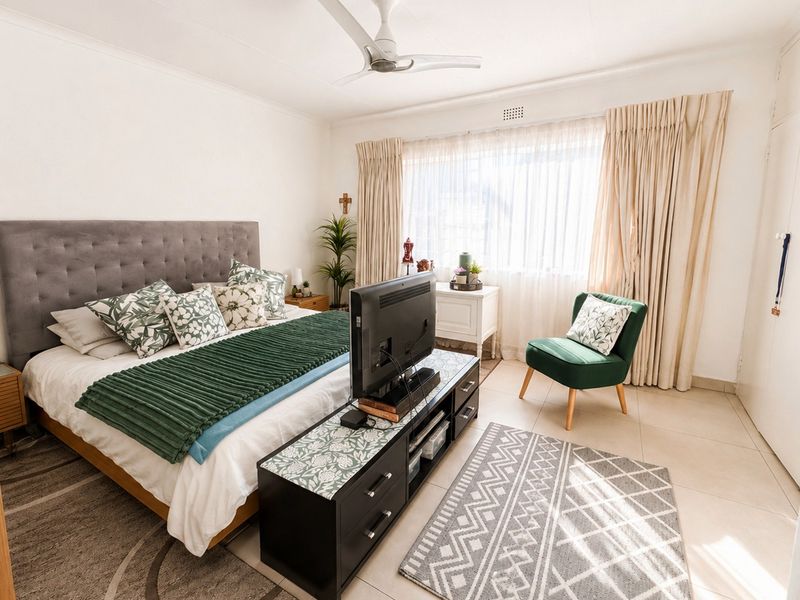 A well-maintained bedroom featuring tiled flooring, a ceiling fan, and built-in storage, offering a bright and comfortable living space.