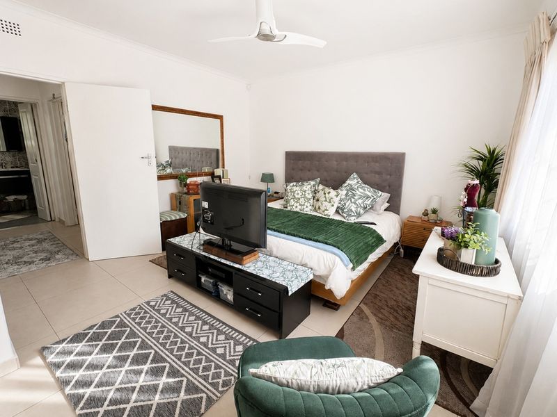 A well-maintained bedroom featuring tiled flooring, a ceiling fan, and direct access to an en-suite bathroom.