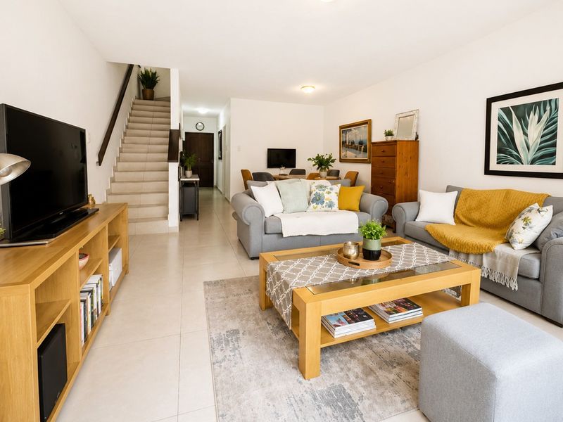 An open-plan living and dining area featuring neutral tiled flooring and a staircase leading to the upper level.