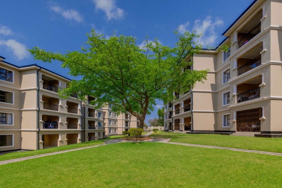 A well-maintained apartment complex featuring multi-story buildings with private balconies, surrounded by landscaped lawns and paved walkways.
