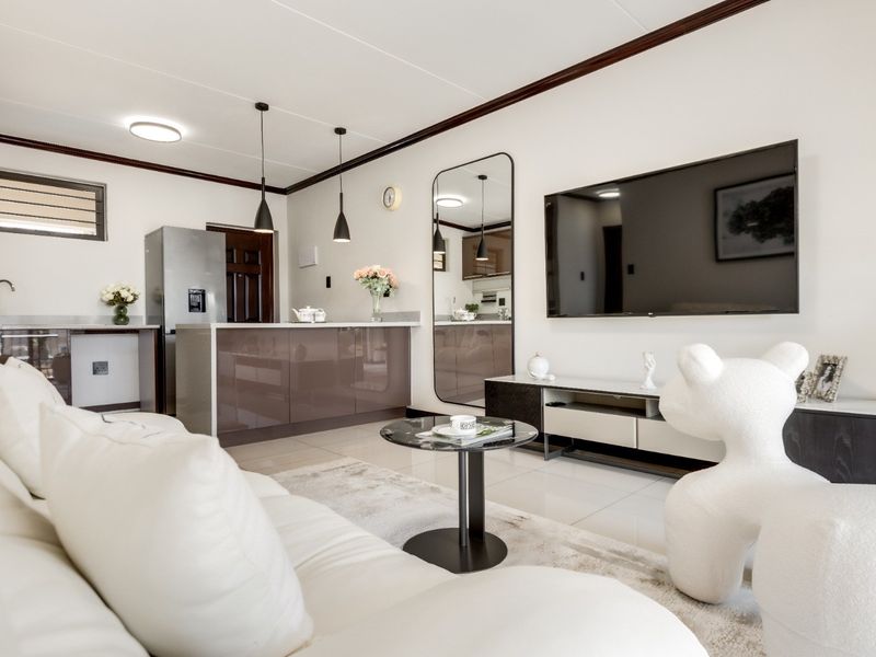 Modern open-plan living area featuring a sleek kitchen with island, tiled flooring, and contemporary pendant lighting, creating a cohesive and functional living space.