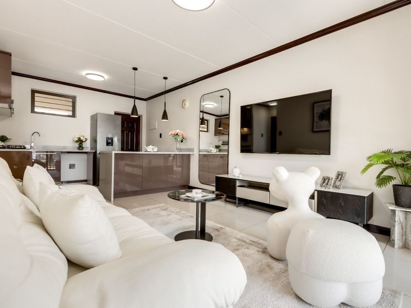 Modern open-plan living area featuring a sleek kitchen with island, tiled floors, and contemporary finishes, creating a bright and functional space.