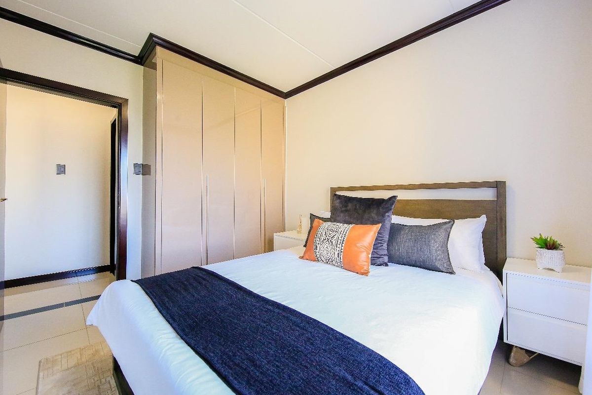 A well-maintained bedroom featuring neutral tiled flooring, built-in cupboards, and decorative coved ceiling detailing.