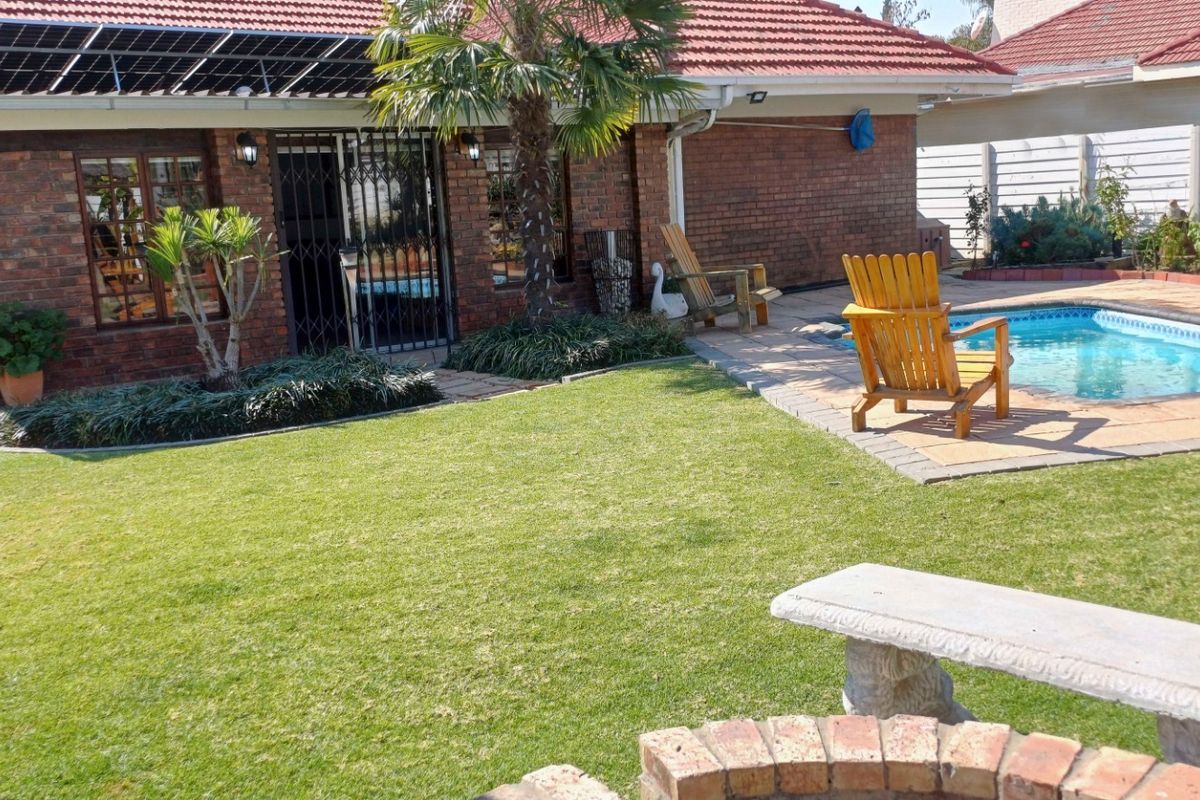Rear garden area featuring a swimming pool, paved surround, and brick house exterior with installed solar panels.