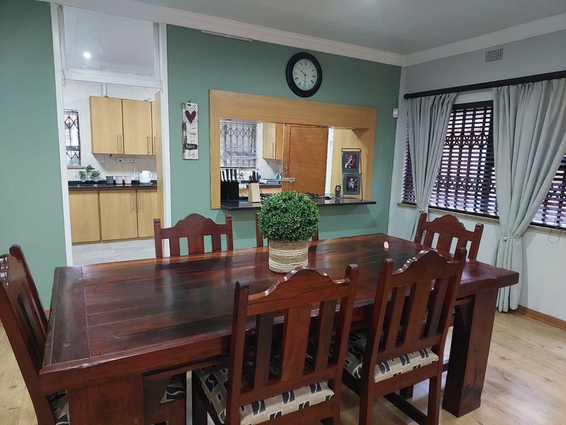 Dining room featuring laminate flooring and a convenient pass-through window connecting to the kitchen area.