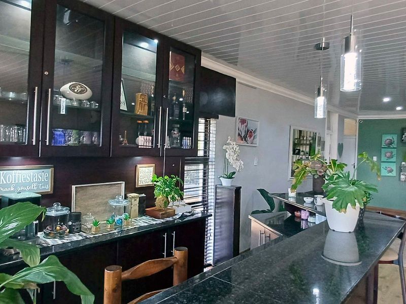 Open plan living area featuring a built-in bar or serving station with dark cabinetry, granite countertops, and modern pendant lighting.