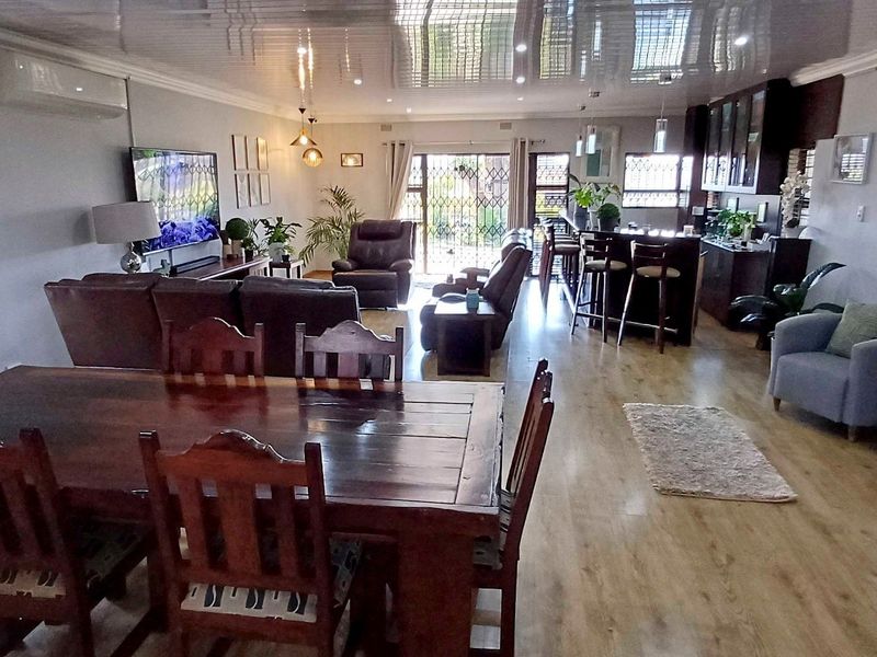 Spacious open-plan living area featuring laminate flooring, a glossy ceiling, and a functional kitchen with a breakfast island.