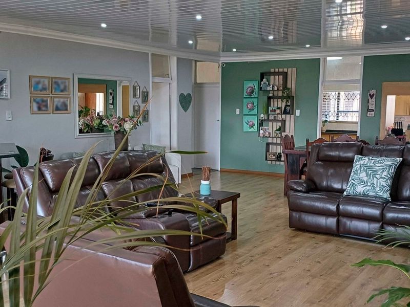 Spacious open-plan living area featuring laminate flooring, glossy ceiling panels, and a breakfast bar, creating a functional and connected home environment.