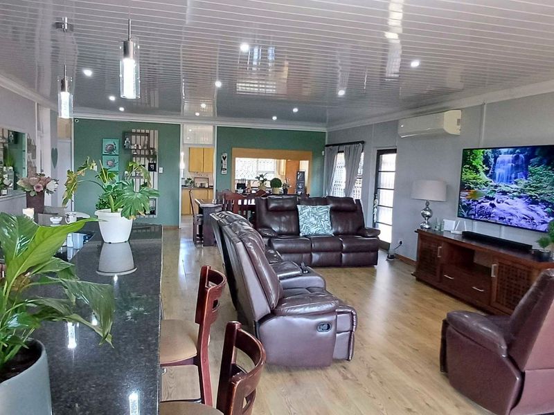 Spacious open-plan living area featuring a granite kitchen island, laminate flooring, and modern recessed lighting, seamlessly connecting the kitchen and lounge spaces.