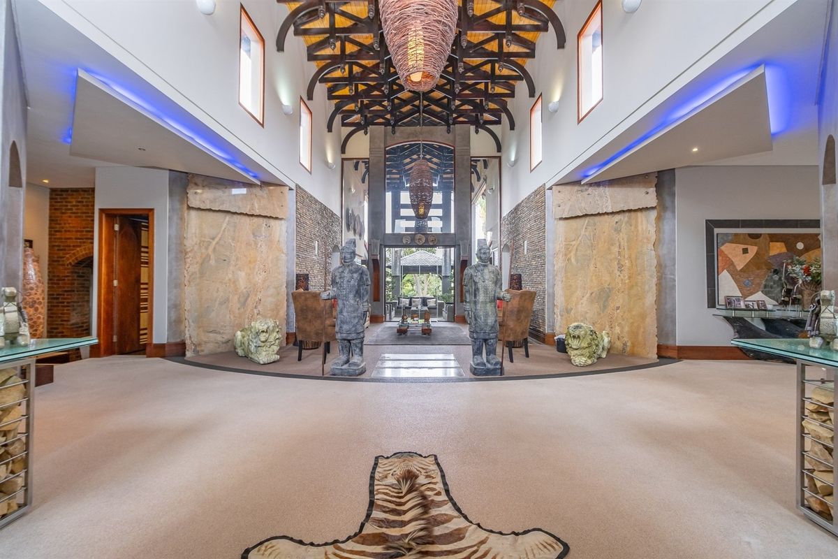 Grand living area featuring high vaulted ceilings with exposed timber trusses, stone feature walls, and sophisticated recessed lighting in a spacious open-plan layout.