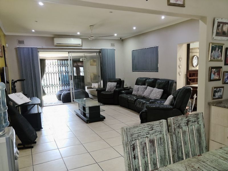 Spacious open-plan living area featuring tiled flooring, recessed lighting, and direct access to an outdoor patio through sliding glass doors.