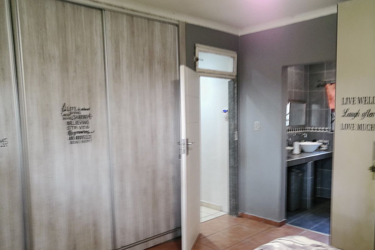 Bedroom featuring built-in cupboards and direct access to an en-suite bathroom with tiled flooring throughout.