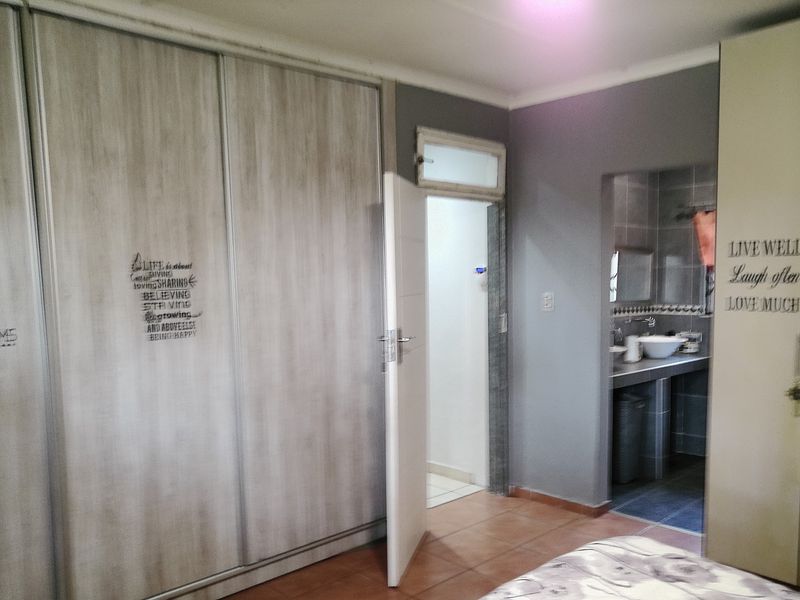 Bedroom featuring built-in cupboards and direct access to an en-suite bathroom with tiled flooring throughout.