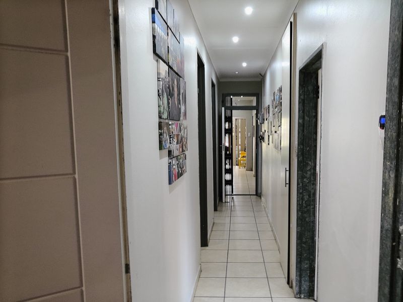 A functional hallway featuring tiled flooring and recessed downlighting, providing access to multiple rooms throughout the property.