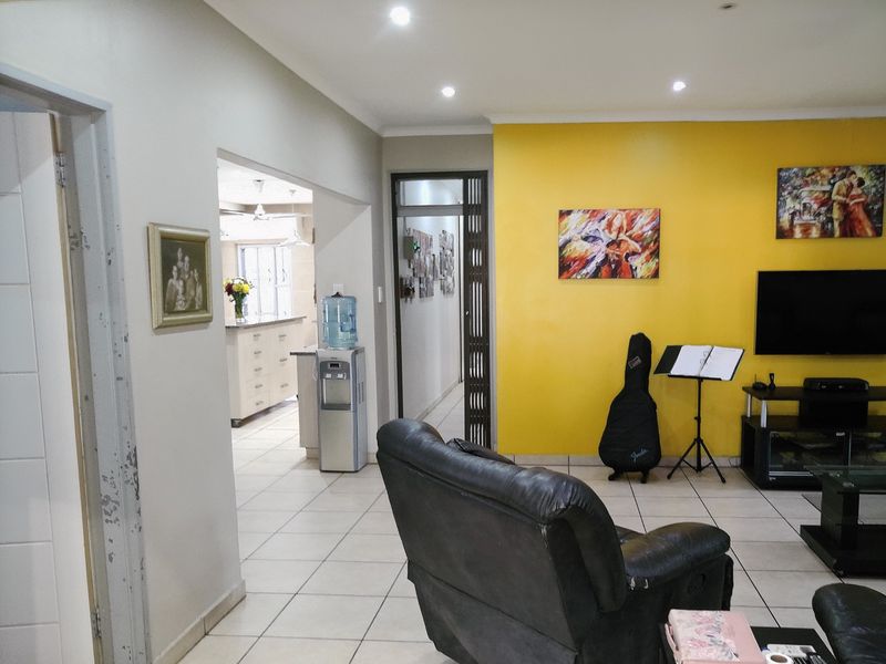 Open plan living area featuring ceramic floor tiles and recessed lighting, with a view through to the adjacent kitchen space.