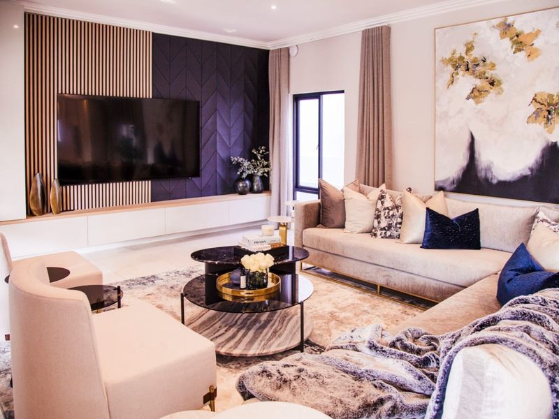 Modern living room featuring a sophisticated media wall with slatted timber and geometric paneling, complemented by high-quality finishes and recessed lighting.