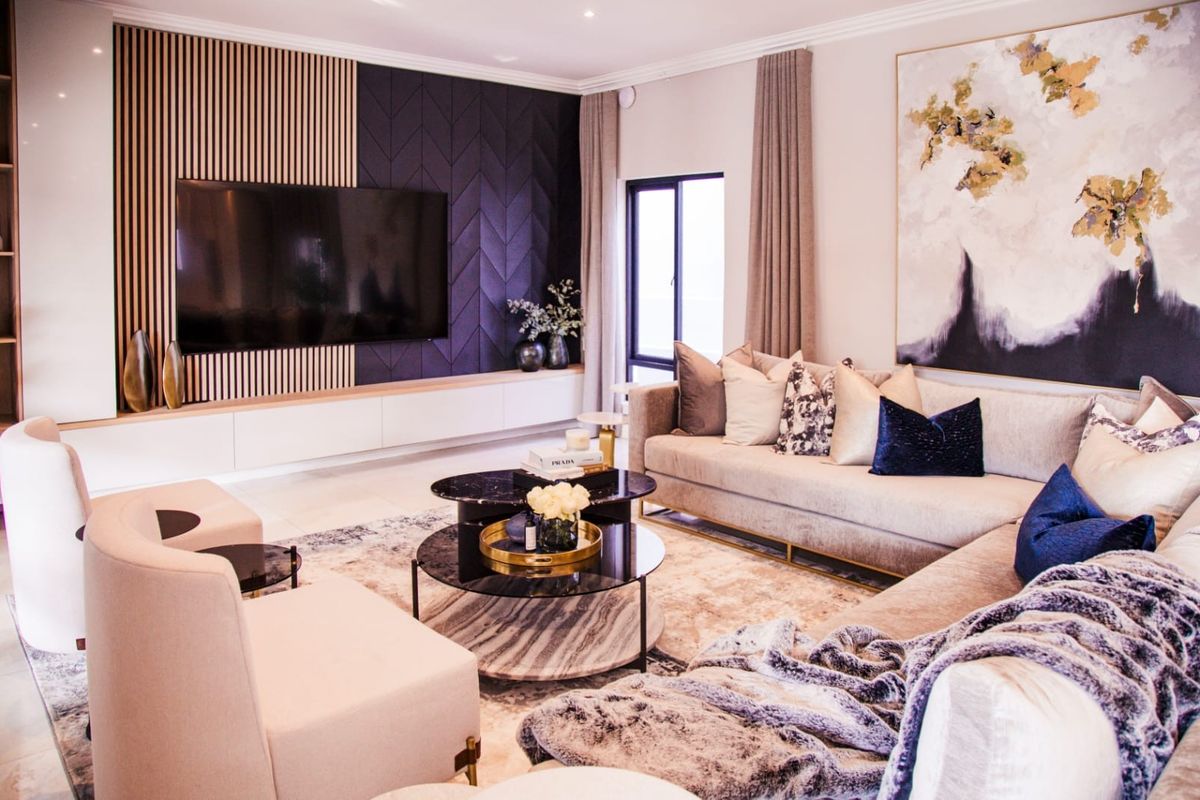 Modern living room featuring a sophisticated media wall with slatted timber and geometric paneling, complemented by high-quality finishes and recessed lighting.