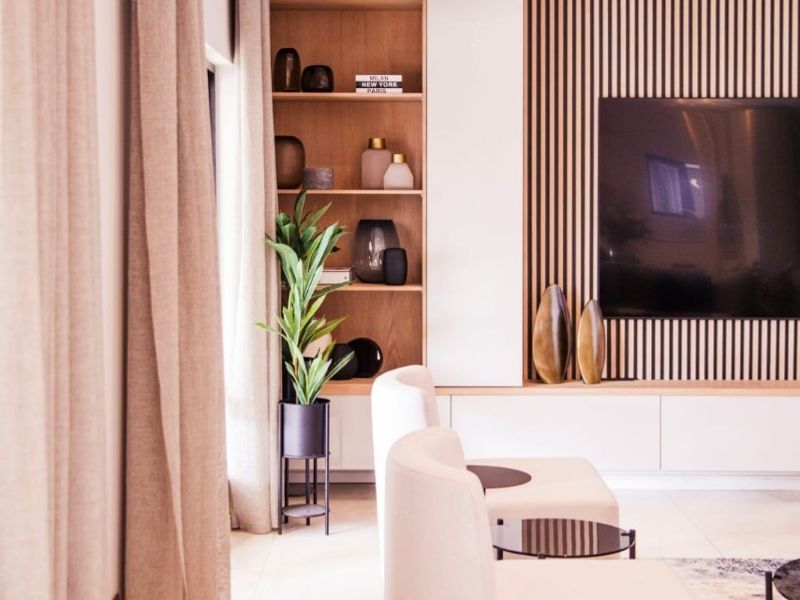 Modern living room featuring custom built-in shelving, elegant slatted timber wall paneling, and polished tiled flooring with recessed lighting.