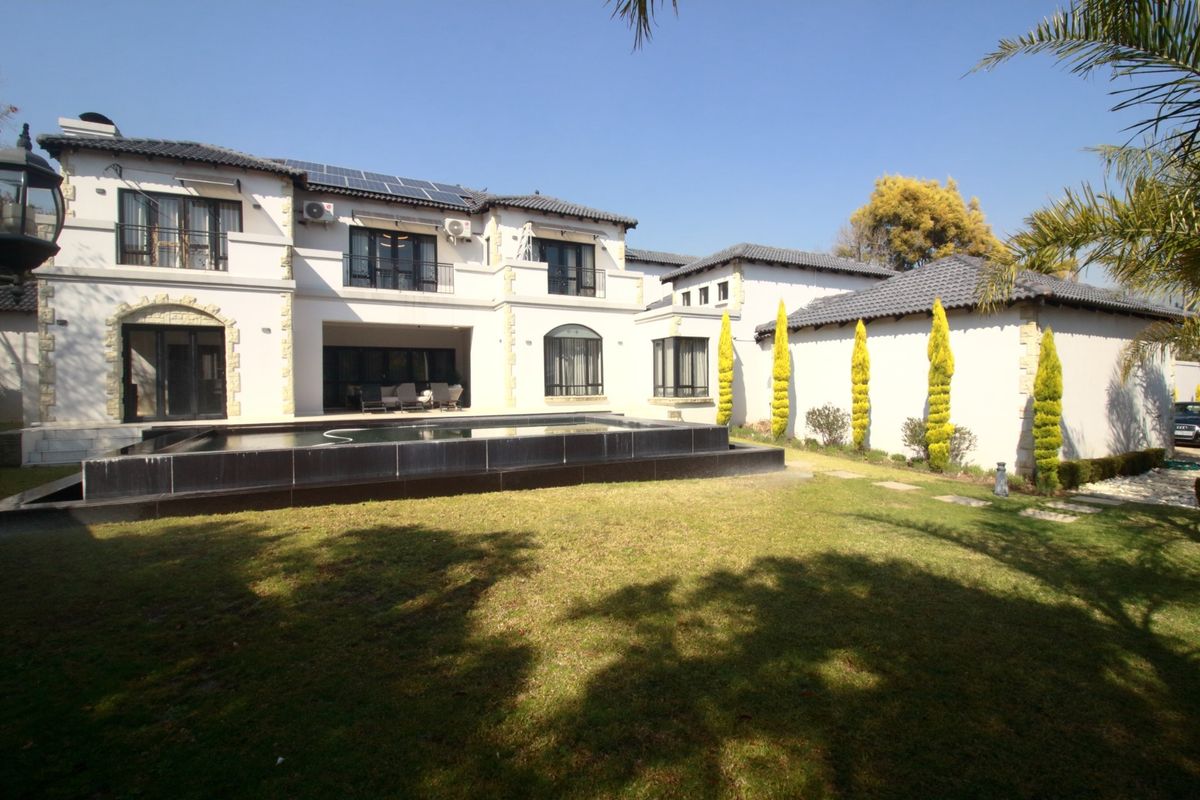 Rear view of a multi-story residence featuring a swimming pool, landscaped garden, balconies, and roof-mounted solar panels.