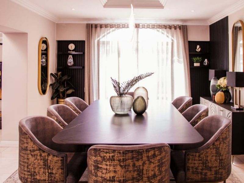 Elegant dining room featuring a recessed ceiling with downlights, built-in shelving, and a large arched window providing natural light.