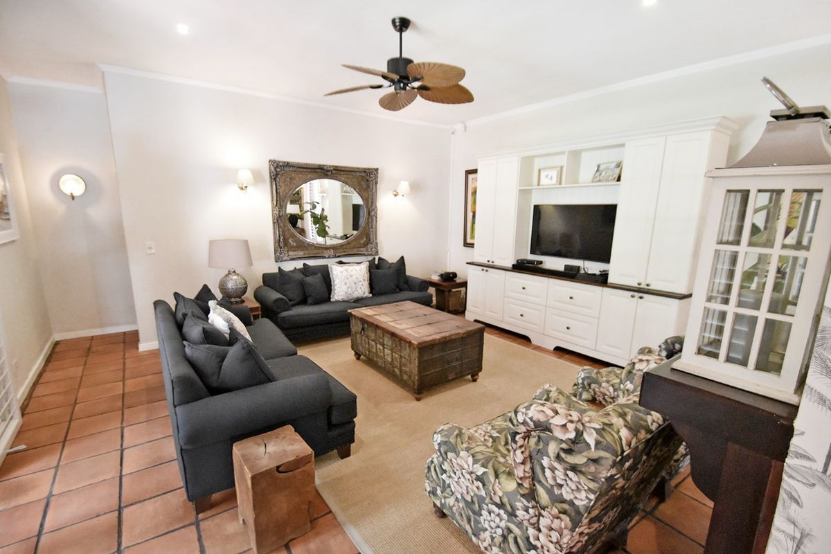 A comfortable living room featuring built-in cabinetry, terracotta floor tiles, and a ceiling fan, providing a warm and functional space for relaxation.