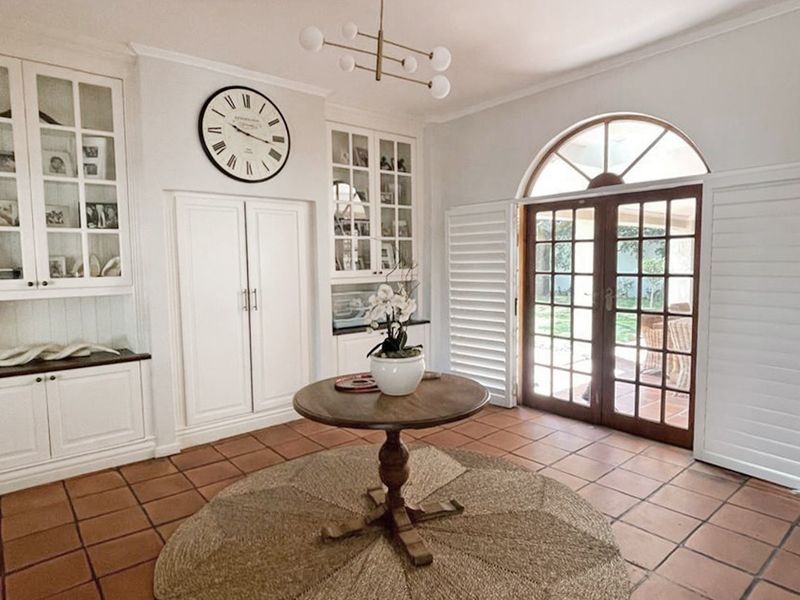 Elegant entrance hall featuring custom built-in cabinetry, terracotta flooring, and arched french doors that open to the garden.