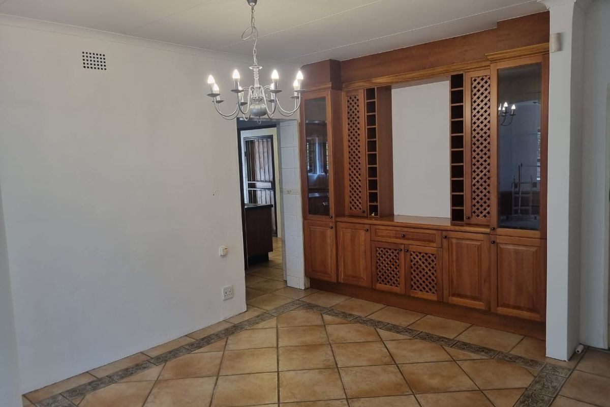 Spacious living area featuring built-in wooden cabinetry, decorative tiled flooring, and a classic chandelier, offering a versatile space for relaxation.