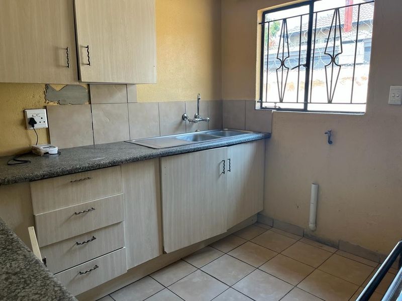 A functional kitchen featuring laminate cabinetry, granite countertops, and a double sink, requiring minor cosmetic repairs and updates to improve its overall condition.