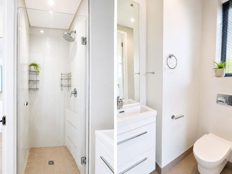 Modern bathroom featuring a glass-enclosed shower, sleek vanity with integrated basin, and a wall-mounted toilet with contemporary finishes.