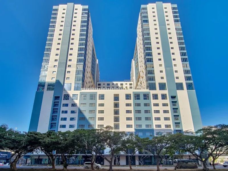 A modern high-rise apartment complex featuring a dual-tower design with glass facades and ground-level commercial frontage.