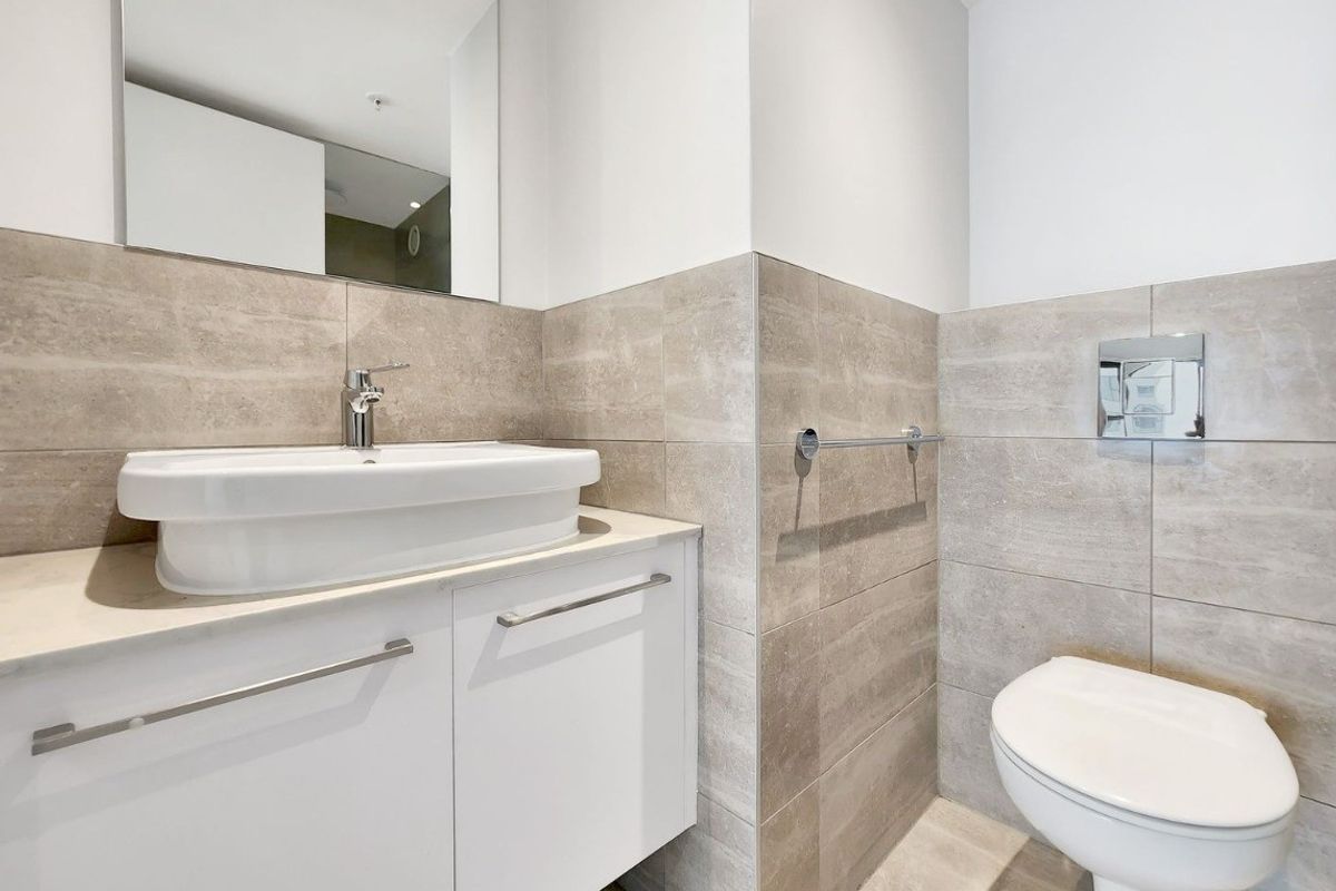Modern bathroom featuring a wall-mounted vanity with a vessel sink, wall-hung toilet with concealed cistern, and neutral ceramic tiling.