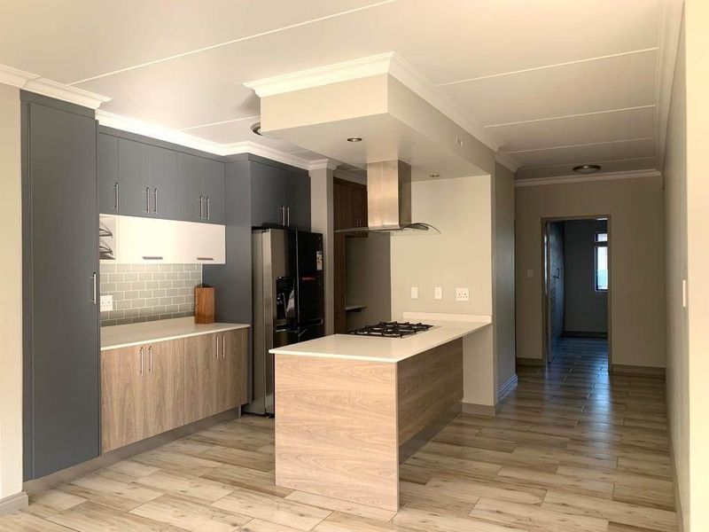 Modern kitchen featuring two-tone cabinetry, stone countertops, a central island with a gas hob, extractor fan, and stylish subway tile backsplash.
