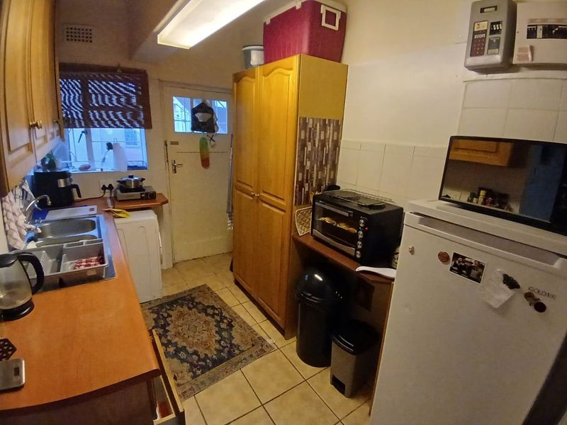 A functional kitchen featuring laminate countertops, a stainless steel sink, tiled flooring, and built-in cabinetry, offering potential for a modern renovation.
