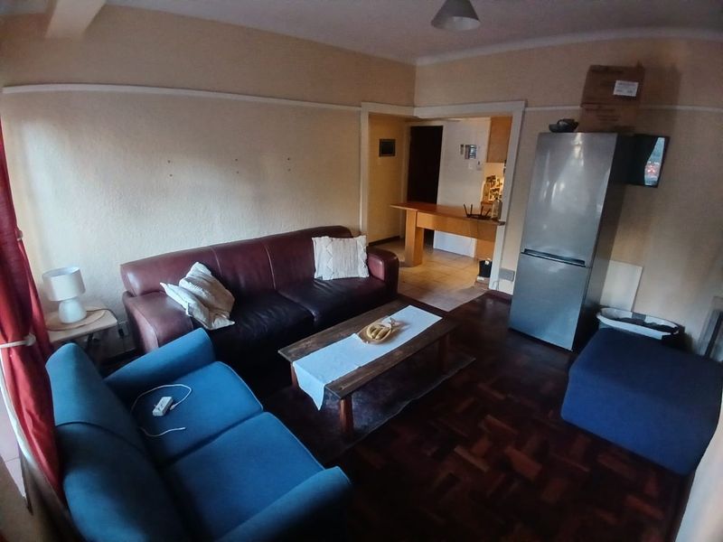 Open-plan living area featuring parquet flooring and a breakfast bar connecting to the kitchen space.
