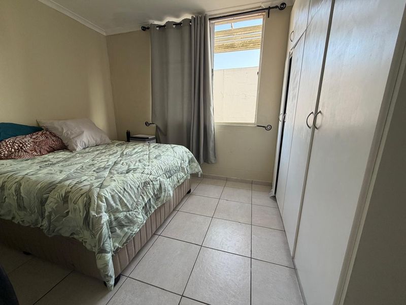 A functional bedroom featuring tiled flooring and built-in cupboards, providing essential storage space.