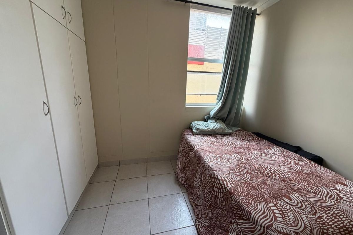 A compact bedroom featuring tiled flooring and built-in cupboards, providing functional storage space.