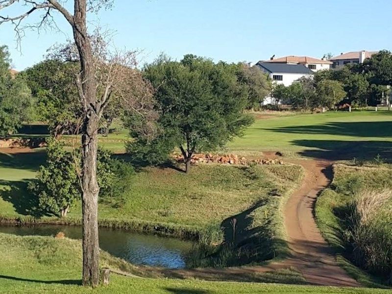 A scenic view overlooking a well-maintained golf course with a small water feature and lush green surroundings.