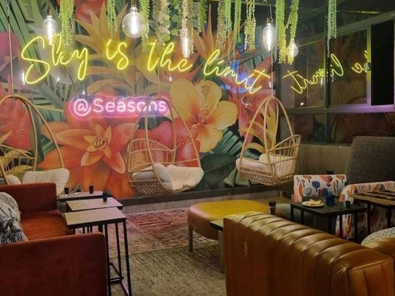 A vibrant, modern living area featuring a bold floral mural, neon signage, and contemporary pendant lighting, creating a stylish and inviting atmosphere.