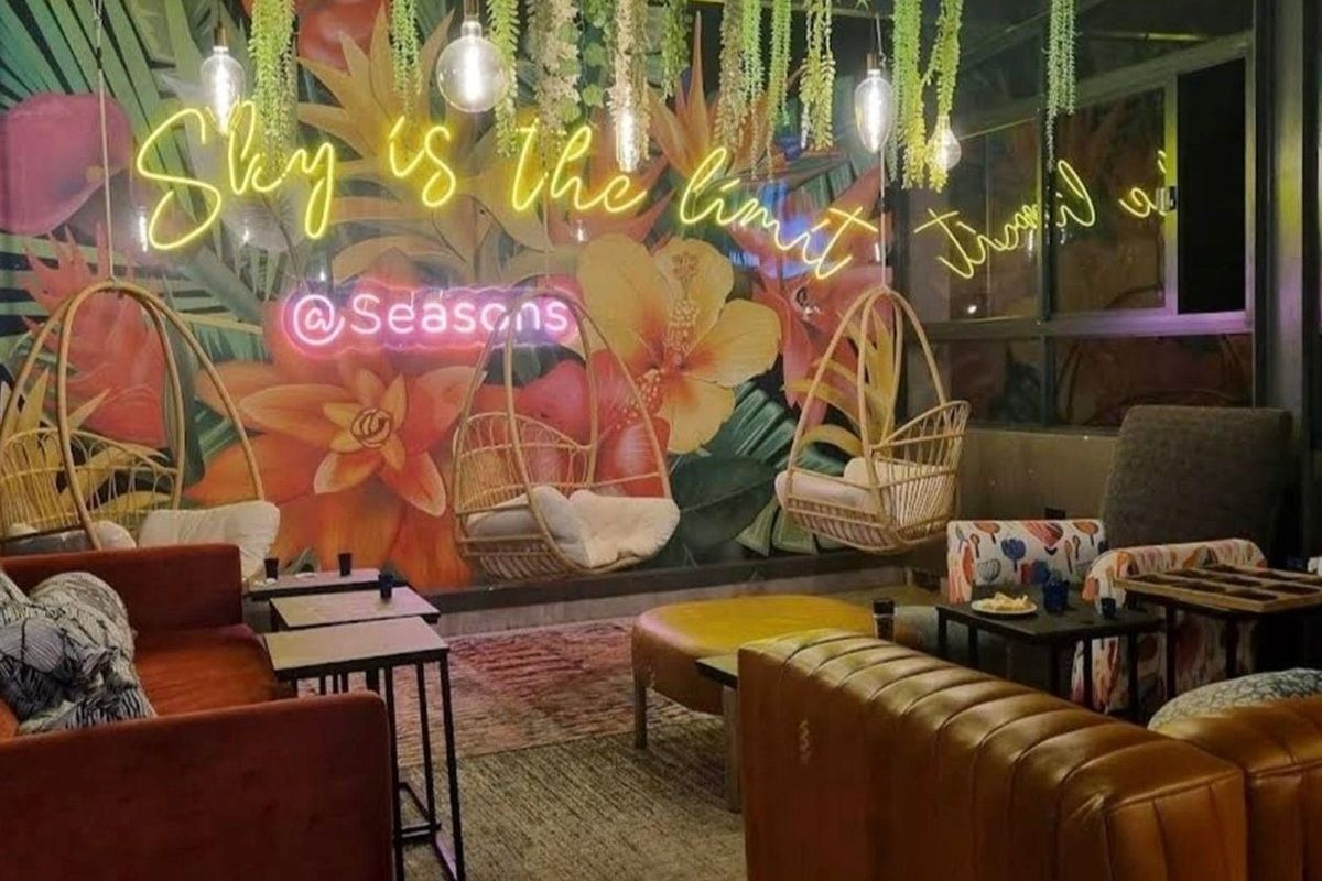 A vibrant, modern living area featuring a bold floral mural, neon signage, and contemporary pendant lighting, creating a stylish and inviting atmosphere.