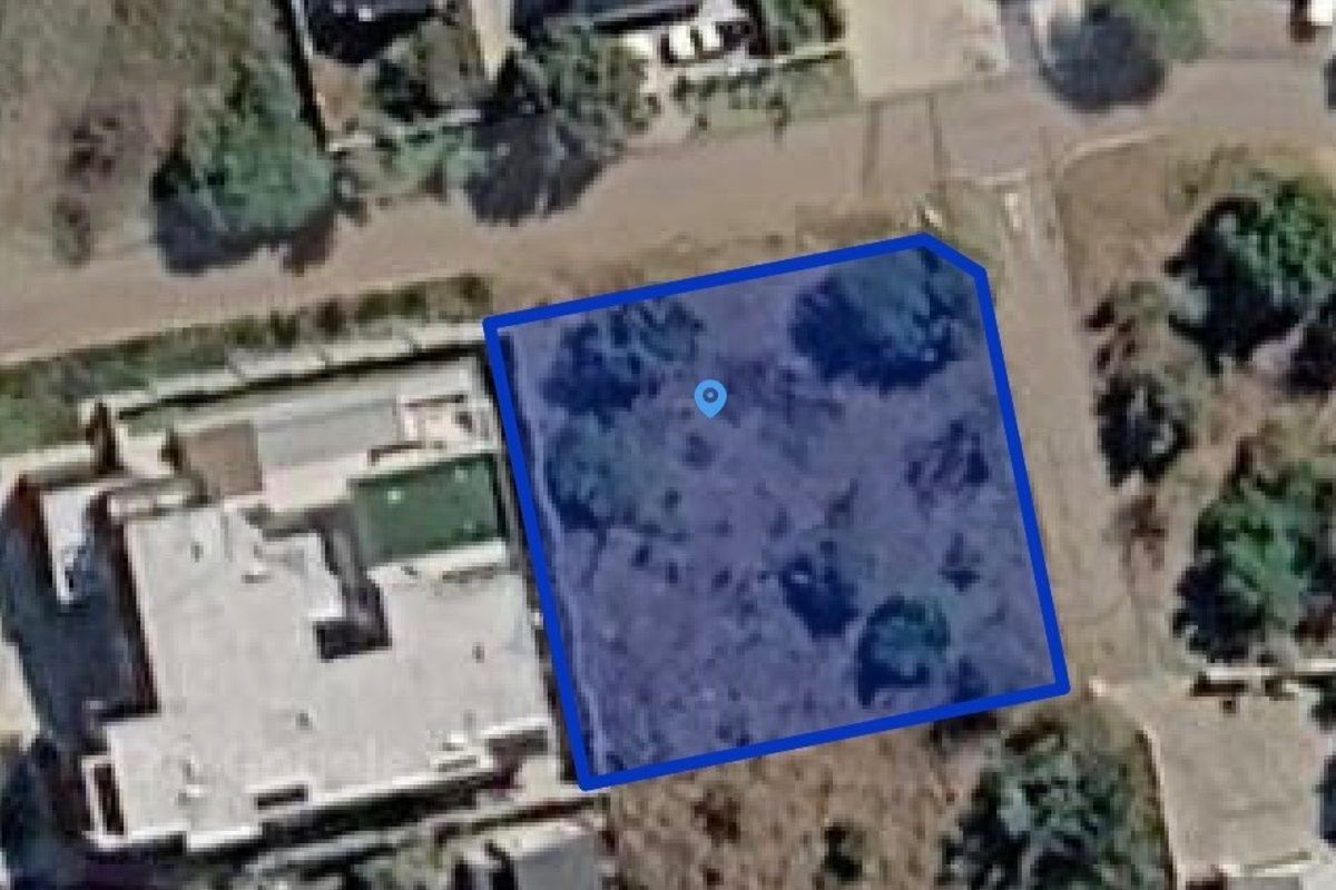 An aerial view of a vacant residential plot, highlighting the property boundaries and surrounding neighborhood context.