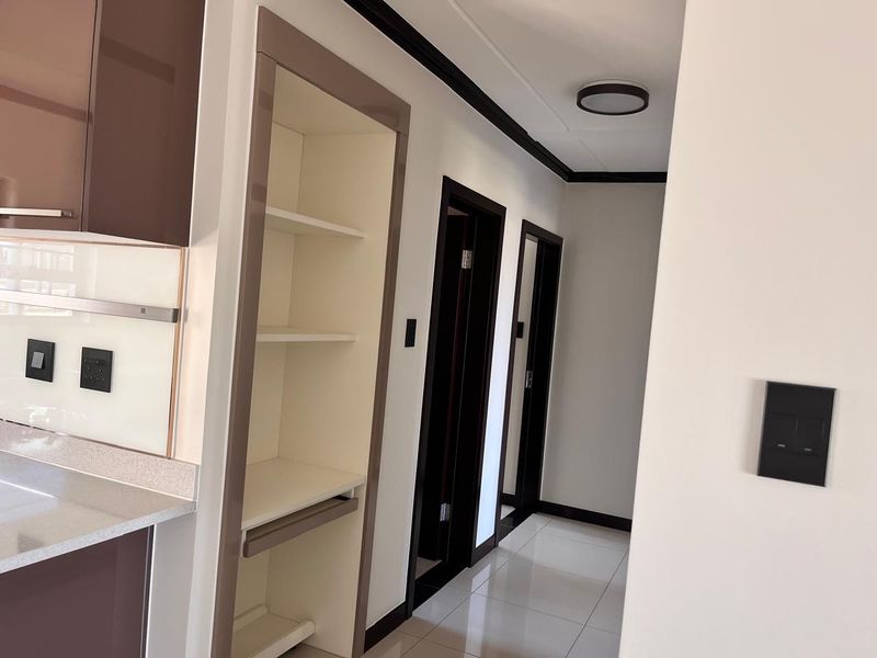 A clean, modern hallway featuring tiled flooring, built-in shelving, and sleek cabinetry, providing a seamless transition between living and private areas.