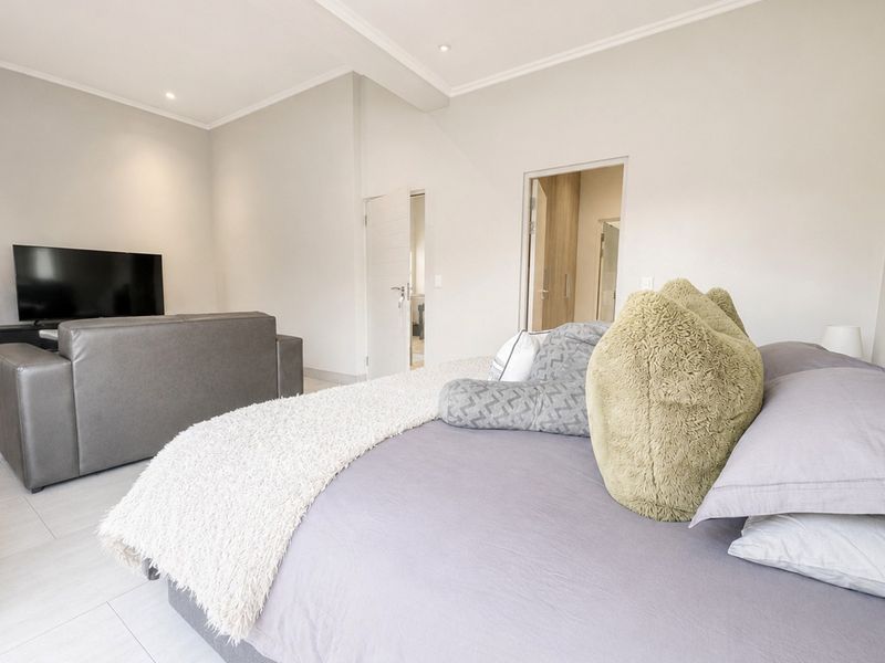 Spacious bedroom featuring neutral tones, tiled flooring, recessed lighting, and direct access to an en-suite bathroom.