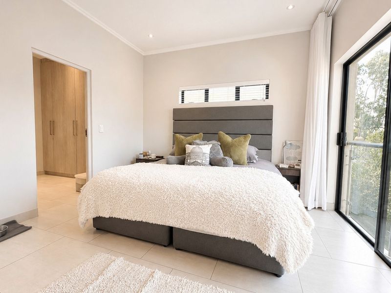 Modern bedroom featuring tiled flooring, built-in cupboards, and a large sliding glass door providing access to an outdoor balcony.