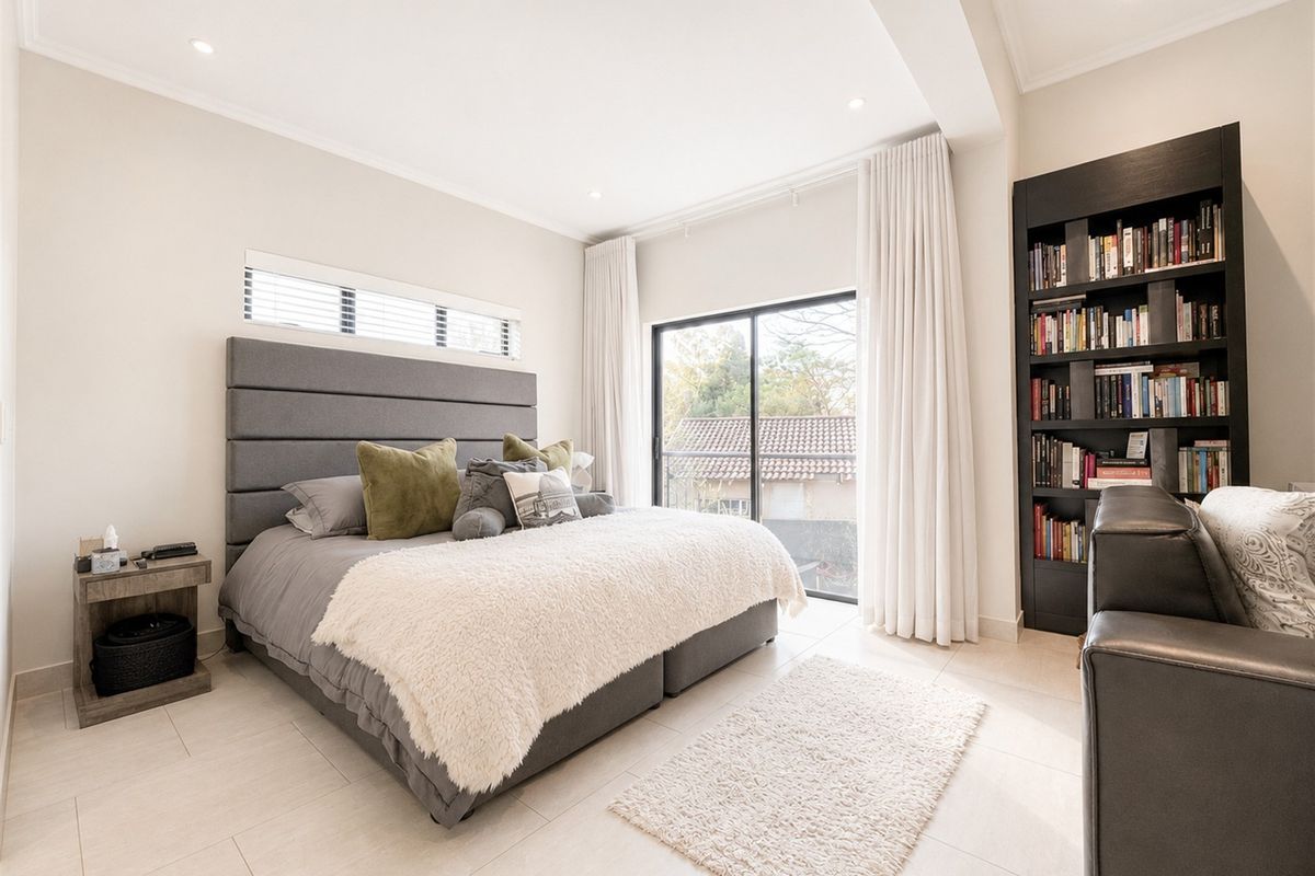 A bright and modern bedroom featuring tiled flooring, recessed lighting, a built-in bookshelf, and a sliding glass door leading to an outdoor area.